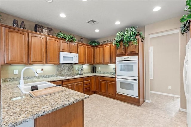 8623 Kennedy Heights Ct, Las Vegas, NV 89131 - kitchen with white appliances, brown cabinets, light stone countertops, recessed lighting, and light tile patterned floors