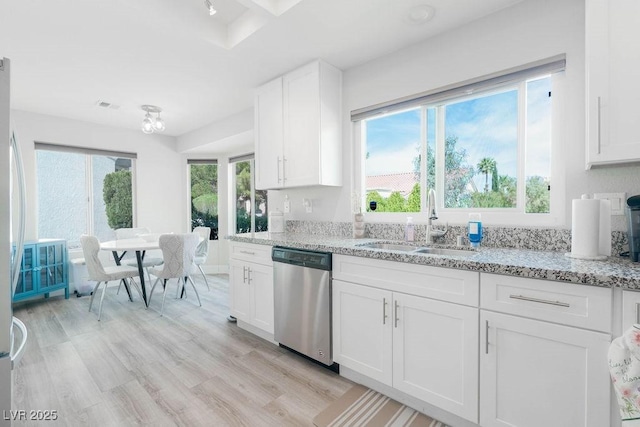 8812 Marble Dr, Las Vegas, NV 89134 - kitchen with stainless steel dishwasher, white cabinets, light stone counters, and light wood-type flooring