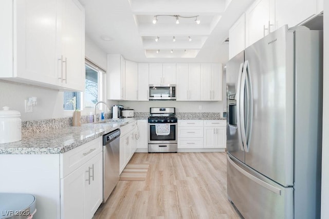 8812 Marble Dr, Las Vegas, NV 89134 - kitchen with appliances with stainless steel finishes, white cabinets, light wood-type flooring, and light stone counters