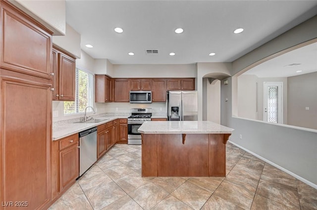 1013 Brinkman St, Las Vegas, NV 89138 - kitchen with stainless steel appliances, arched walkways, a center island, recessed lighting, and light stone counters