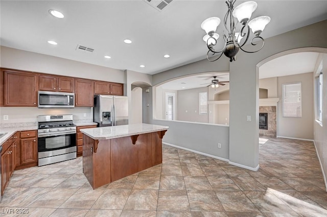 1013 Brinkman St, Las Vegas, NV 89138 - kitchen featuring stainless steel appliances, arched walkways, a tile fireplace, recessed lighting, and brown cabinetry
