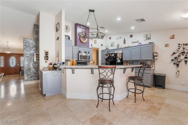 7517 Elk Meadows Ct, Las Vegas, NV 89131 - kitchen featuring freestanding refrigerator, stainless steel microwave, a peninsula, a kitchen breakfast bar, and gray cabinetry