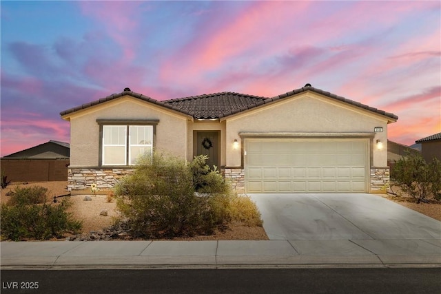 3568 E Malheur Ave, Pahrump, NV 89061 - view of front of home with stone siding, stucco siding, a garage, driveway, and a tiled roof