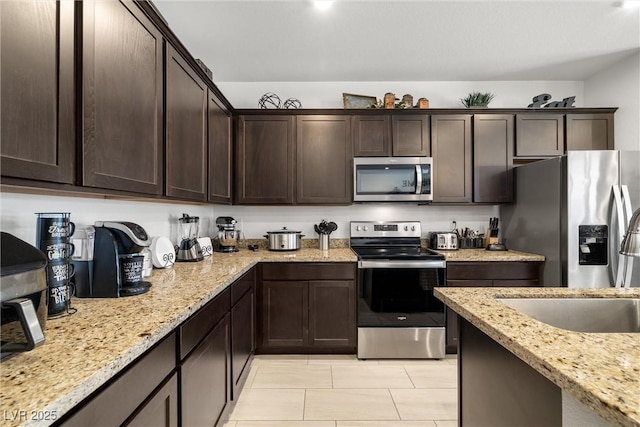 3568 E Malheur Ave, Pahrump, NV 89061 - kitchen featuring appliances with stainless steel finishes, dark brown cabinetry, light tile patterned floors, and light stone counters