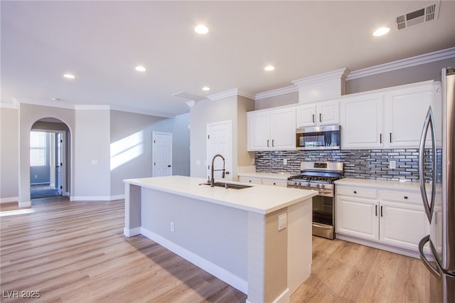 8026 Sunset Creek St, Las Vegas, NV 89113 - kitchen featuring stainless steel appliances, an island with sink, ornamental molding, arched walkways, and tasteful backsplash