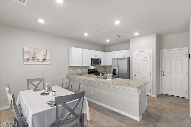 4498 Lantern Point Ave, North Las Vegas, NV 89084 - kitchen featuring appliances with stainless steel finishes, a peninsula, white cabinetry, light stone countertops, and recessed lighting