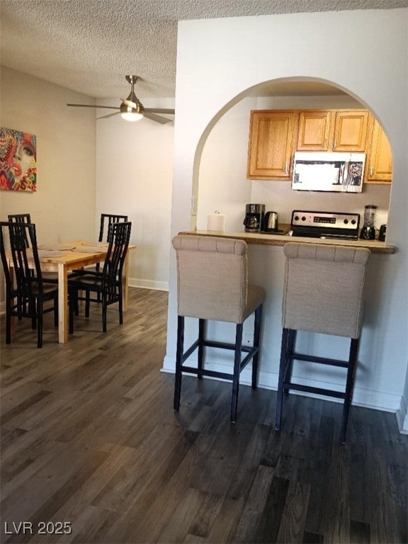 1515 E Reno Ave Unit D202, Las Vegas, NV 89119 - kitchen featuring electric range oven, a ceiling fan, dark wood-style floors, arched walkways, and a textured ceiling