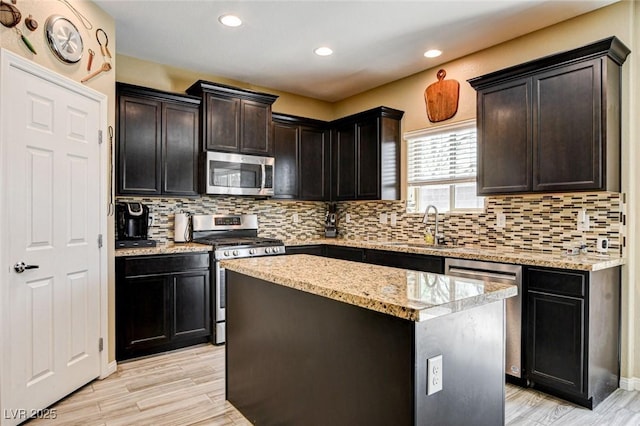 6897 Linda Creek Ct, Las Vegas, NV 89178 - kitchen with appliances with stainless steel finishes, tasteful backsplash, a kitchen island, light stone counters, and light wood-style floors