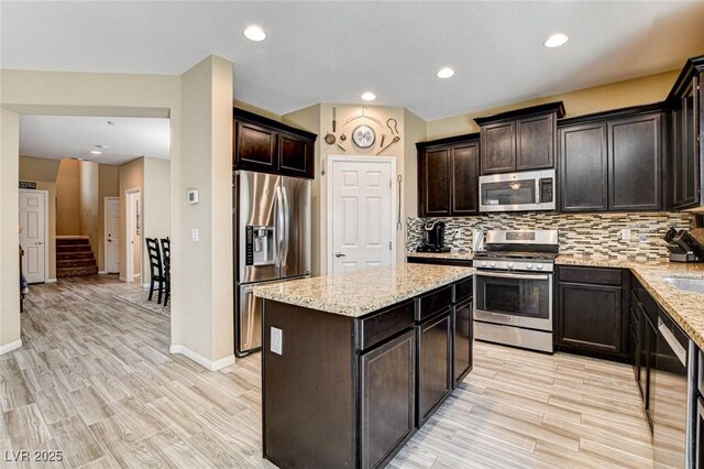 6897 Linda Creek Ct, Las Vegas, NV 89178 - kitchen featuring stainless steel appliances, light wood-style floors, a kitchen island, backsplash, and recessed lighting