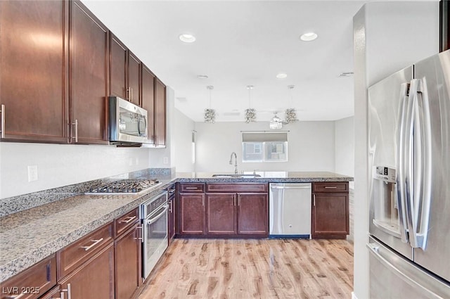 3908 Total Eclipse St, Las Vegas, NV 89129 - kitchen with appliances with stainless steel finishes, light wood finished floors, a peninsula, stone counters, and recessed lighting
