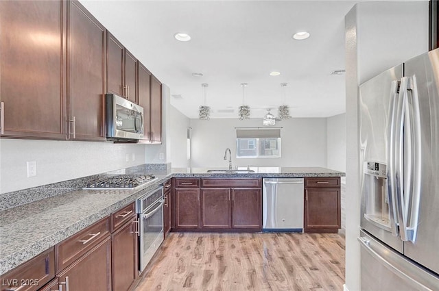 3908 Total Eclipse St, Las Vegas, NV 89129 - kitchen with appliances with stainless steel finishes, light wood finished floors, a peninsula, light stone countertops, and recessed lighting