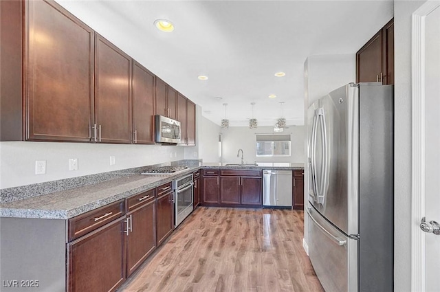 3908 Total Eclipse St, Las Vegas, NV 89129 - kitchen with appliances with stainless steel finishes, light wood-style floors, a peninsula, light countertops, and dark brown cabinetry
