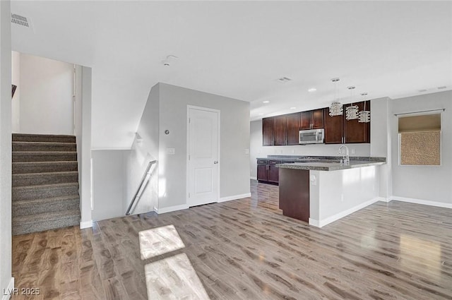 3908 Total Eclipse St, Las Vegas, NV 89129 - kitchen with stainless steel microwave, light wood finished floors, open floor plan, a peninsula, and recessed lighting