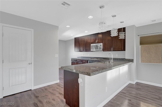 3908 Total Eclipse St, Las Vegas, NV 89129 - kitchen featuring stainless steel microwave, dark wood finished floors, dark brown cabinets, dark countertops, and recessed lighting