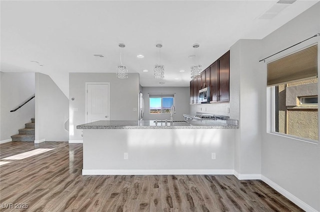 3908 Total Eclipse St, Las Vegas, NV 89129 - kitchen featuring stainless steel microwave, wood finished floors, dark brown cabinets, hanging light fixtures, and recessed lighting