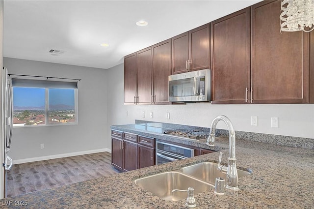 3908 Total Eclipse St, Las Vegas, NV 89129 - kitchen with stainless steel appliances, wood finished floors, dark stone countertops, recessed lighting, and dark brown cabinets