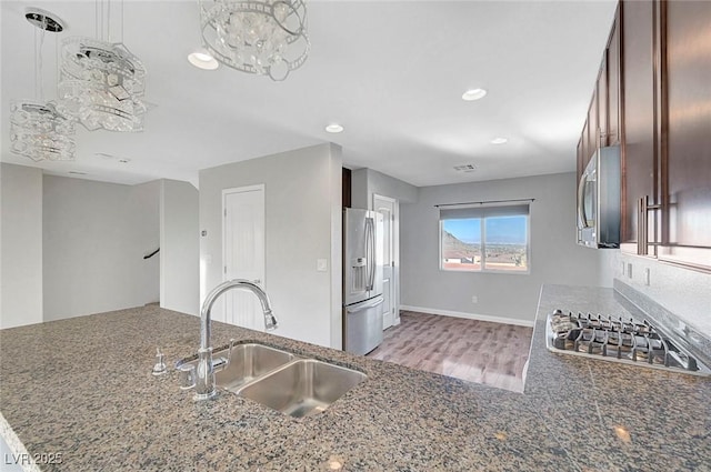 3908 Total Eclipse St, Las Vegas, NV 89129 - kitchen with appliances with stainless steel finishes, recessed lighting, dark stone counters, light wood-style floors, and a chandelier