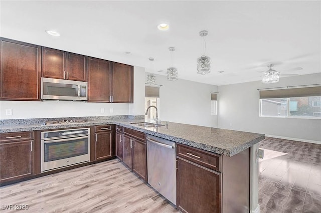 3908 Total Eclipse St, Las Vegas, NV 89129 - kitchen with stainless steel appliances, a peninsula, light wood-style flooring, dark brown cabinetry, and ceiling fan