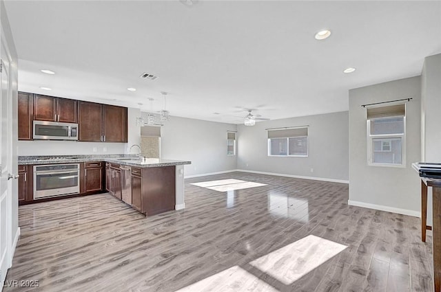 3908 Total Eclipse St, Las Vegas, NV 89129 - kitchen featuring appliances with stainless steel finishes, a peninsula, a ceiling fan, recessed lighting, and light wood-type flooring