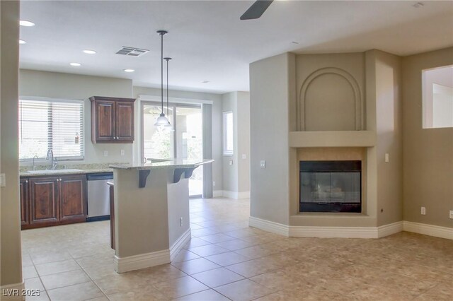 72 Broken Putter Way, Las Vegas, NV 89148 - kitchen with stainless steel dishwasher, a breakfast bar, light stone countertops, hanging light fixtures, and a ceiling fan