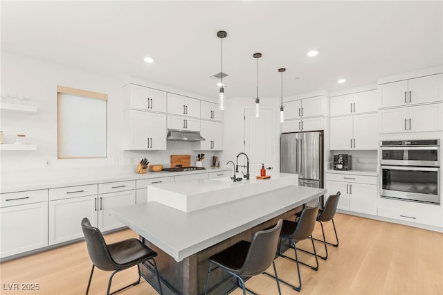 389 Red Feather Peak Ct, Las Vegas, NV 89138 - kitchen featuring appliances with stainless steel finishes, under cabinet range hood, a breakfast bar, white cabinetry, and recessed lighting