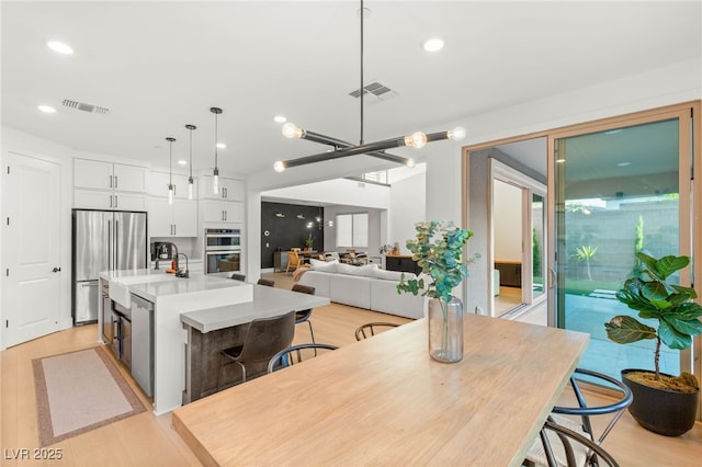 389 Red Feather Peak Ct, Las Vegas, NV 89138 - kitchen with stainless steel appliances, white cabinets, a center island with sink, light countertops, and pendant lighting