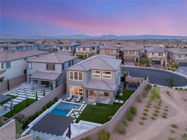 389 Red Feather Peak Ct, Las Vegas, NV 89138 - back of property at dusk with a residential view, a fenced backyard, stucco siding, a tiled roof, and a patio