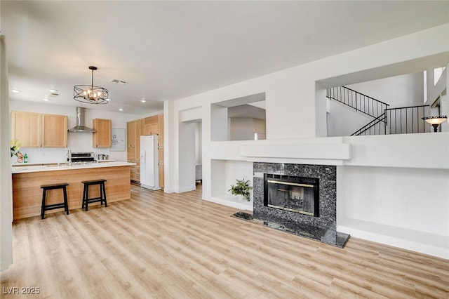 6652 Coral Springs Cir, Las Vegas, NV 89108 - unfurnished living room with light wood-style flooring, a chandelier, a fireplace, and stairs