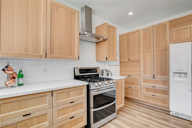 6652 Coral Springs Cir, Las Vegas, NV 89108 - kitchen featuring white refrigerator with ice dispenser, range with two ovens, wall chimney range hood, light brown cabinetry, and recessed lighting