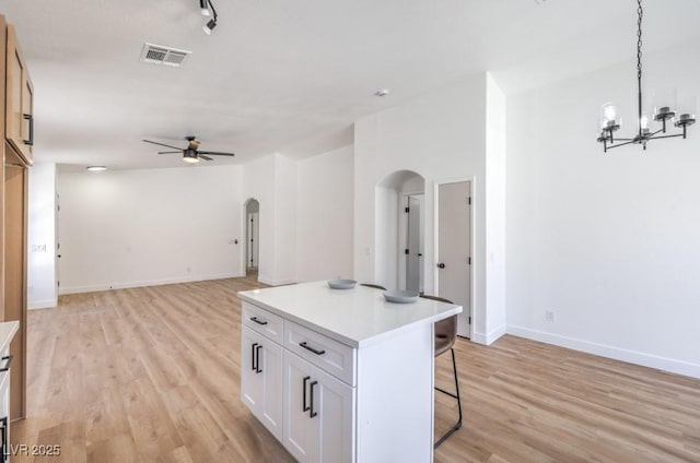 6456 First View Ave, Las Vegas, NV 89142 - kitchen with arched walkways, ceiling fan, a breakfast bar, light wood-type flooring, and white cabinets