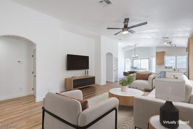 6456 First View Ave, Las Vegas, NV 89142 - living area featuring arched walkways, light wood-style floors, vaulted ceiling, a ceiling fan, and a chandelier
