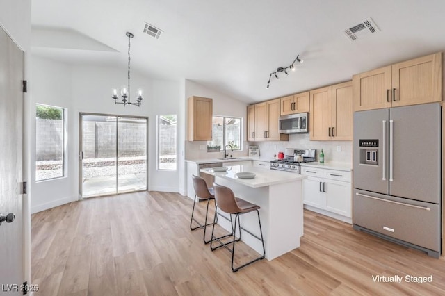 6456 First View Ave, Las Vegas, NV 89142 - kitchen featuring appliances with stainless steel finishes, light countertops, light wood-type flooring, lofted ceiling, and light brown cabinetry