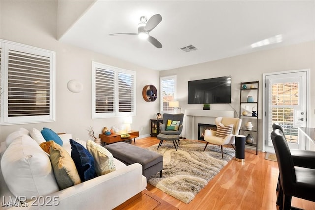 262 Cielito Lindo St, Henderson, NV 89012 - living area featuring a ceiling fan, healthy amount of natural light, wood finished floors, and a warm lit fireplace
