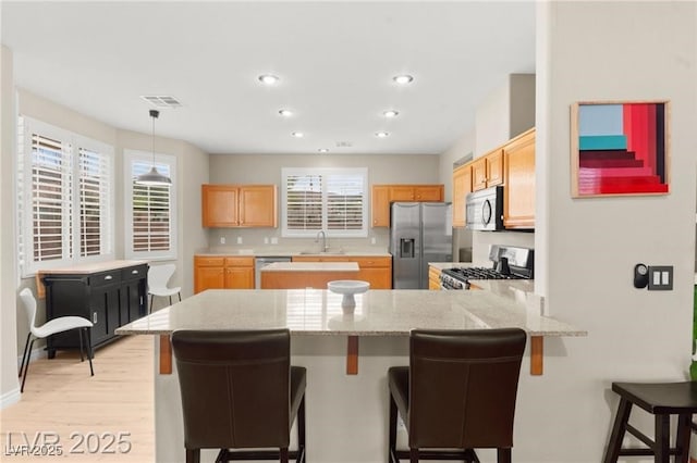 262 Cielito Lindo St, Henderson, NV 89012 - kitchen featuring appliances with stainless steel finishes, a peninsula, light wood finished floors, healthy amount of natural light, and recessed lighting