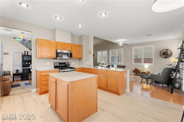 262 Cielito Lindo St, Henderson, NV 89012 - kitchen featuring stainless steel appliances, open floor plan, a peninsula, light countertops, and light wood-style floors