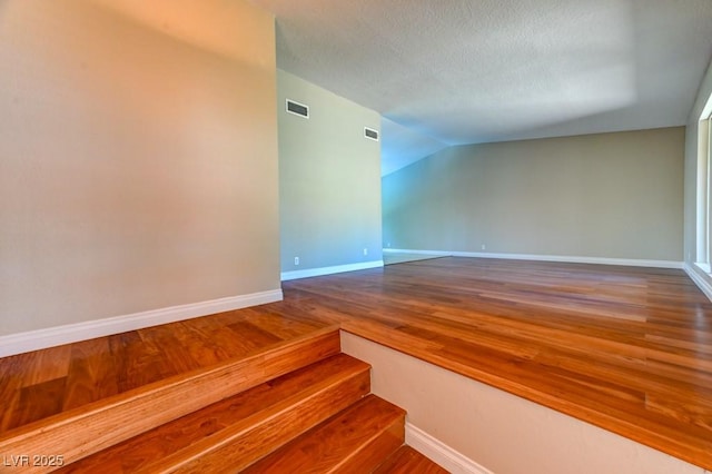 8729 Pesaro Dr, Las Vegas, NV 89117 - stairs with wood finished floors, vaulted ceiling, and a textured ceiling