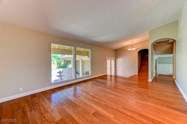 8729 Pesaro Dr, Las Vegas, NV 89117 - spare room featuring arched walkways, stairs, light wood-style floors, a chandelier, and a textured ceiling
