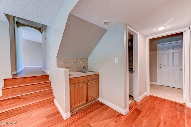 8729 Pesaro Dr, Las Vegas, NV 89117 - stairs featuring wood finished floors, a textured ceiling, arched walkways, and vaulted ceiling