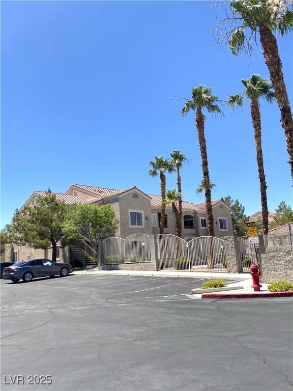 9470 Peace Way Unit 212, Las Vegas, NV 89147 - view of front of house featuring a gate, uncovered parking, a tile roof, and stucco siding