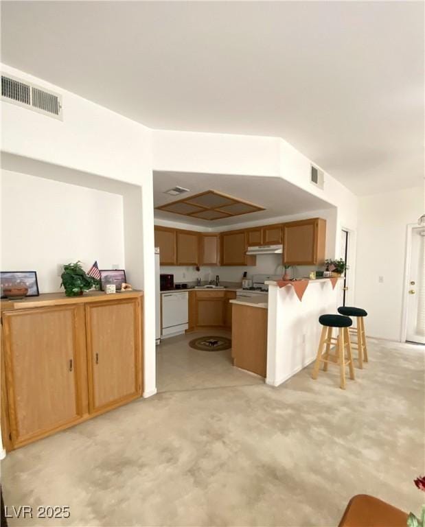 9470 Peace Way Unit 212, Las Vegas, NV 89147 - kitchen featuring a peninsula, a kitchen breakfast bar, light carpet, white appliances, and under cabinet range hood