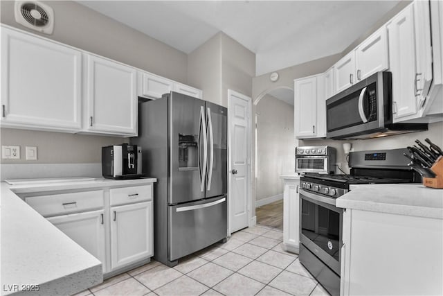 2512 Huber Heights Dr, Las Vegas, NV 89128 - kitchen with stainless steel appliances, white cabinetry, light countertops, arched walkways, and light tile patterned flooring