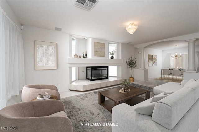9604 Summer Cypress St, Las Vegas, NV 89123 - living room featuring ornate columns, a chandelier, arched walkways, and a tiled fireplace