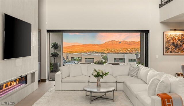 12 Desert Lake Ln, Henderson, NV 89011 - living area featuring a glass covered fireplace, light tile patterned flooring, a mountain view, and a high ceiling