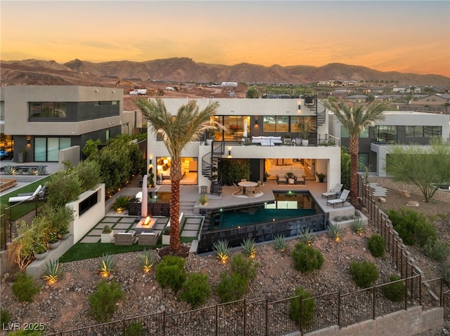 12 Desert Lake Ln, Henderson, NV 89011 - back of property at dusk featuring an outdoor living space, a balcony, a fenced backyard, a mountain view, and stairs