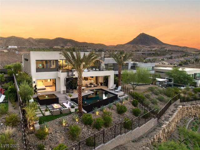 12 Desert Lake Ln, Henderson, NV 89011 - back of property at dusk with a balcony, a mountain view, stairway, a fenced backyard, and an outdoor hangout area