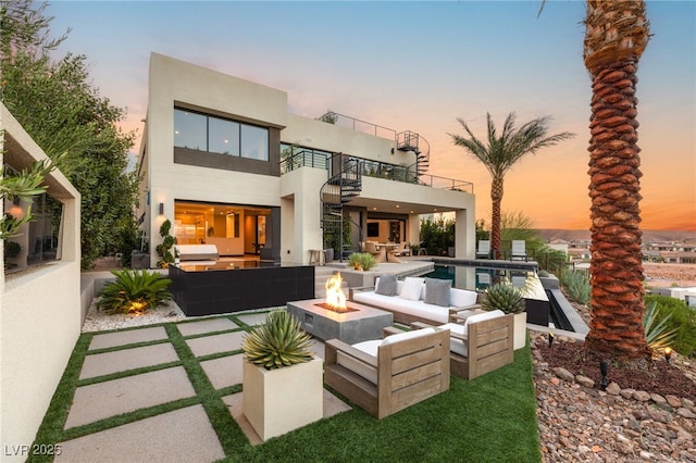 12 Desert Lake Ln, Henderson, NV 89011 - back of house at dusk with a balcony, an outdoor living space with a fire pit, stucco siding, a patio area, and an outdoor pool