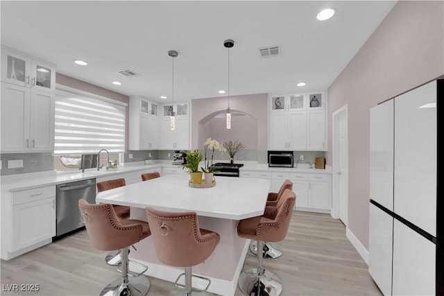 5788 Robin Ridge Ave, Las Vegas, NV 89141 - kitchen featuring appliances with stainless steel finishes, light countertops, a kitchen island, glass insert cabinets, and a breakfast bar