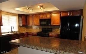 1851 Hillpointe Rd Unit 1711, Henderson, NV 89074 - kitchen with black appliances, a tray ceiling, brown cabinets, and dark stone counters