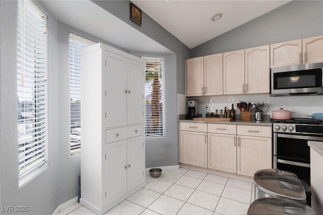 998 Hunters Run Dr, Henderson, NV 89002 - kitchen featuring appliances with stainless steel finishes, lofted ceiling, backsplash, light tile patterned floors, and light brown cabinetry