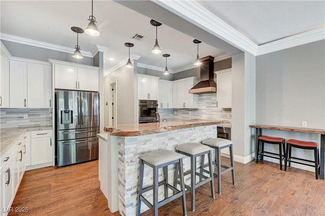 5913 Audria Falls Ave, Las Vegas, NV 89131 - kitchen with stainless steel fridge, wall chimney exhaust hood, decorative backsplash, light stone countertops, and a kitchen bar